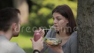年轻的素食夫妇<strong>坐在公园里</strong>吃沙拉和喝冰沙
